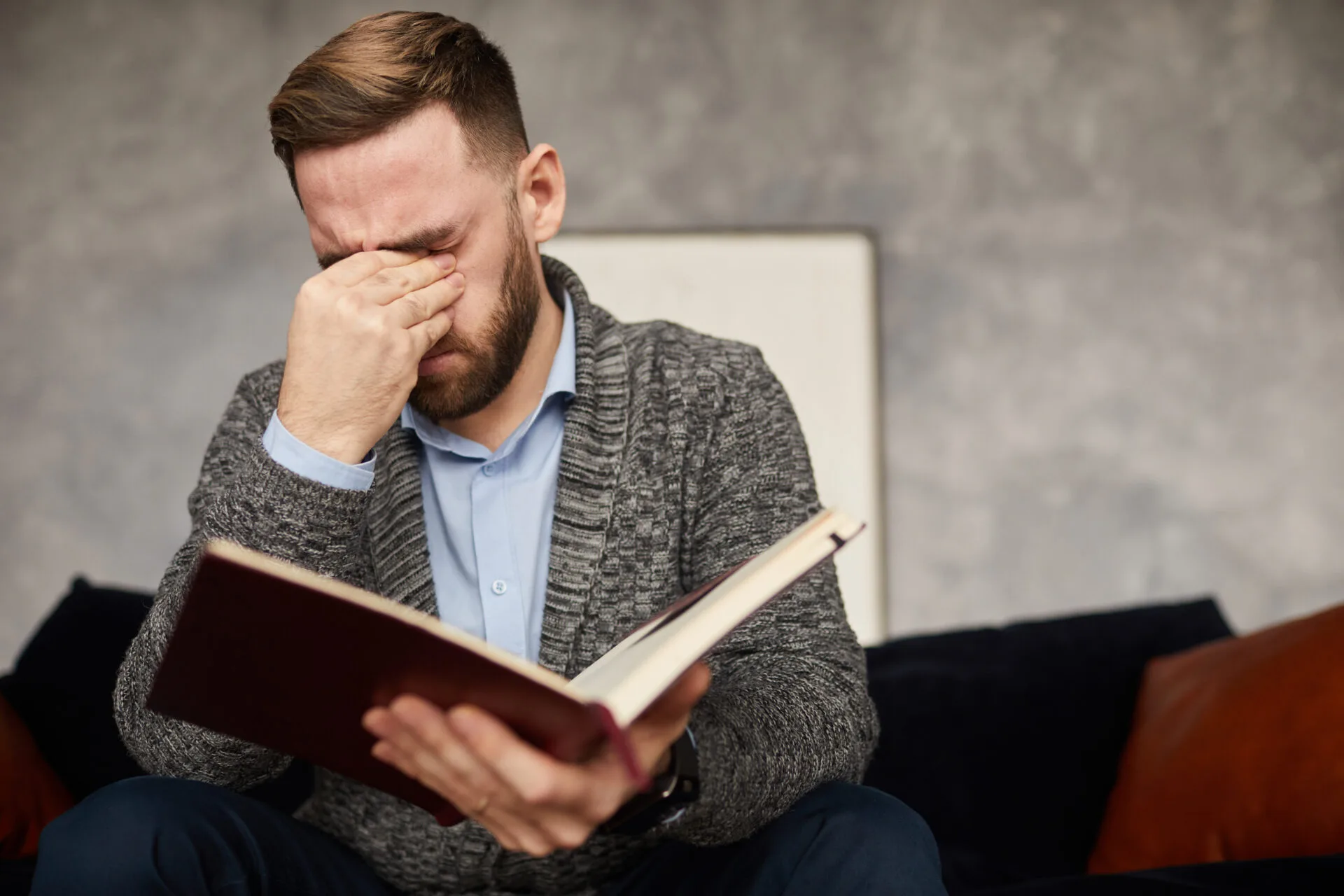 Pessoa com expressão de desconforto tentando ler um texto com a mão na testa, demonstrando esforço visual